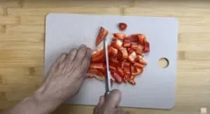 Chopping a red bell pepper on a cutting board for a fresh, healthy meal prep.